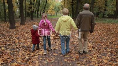 Grandparents with kids walking along autumn path