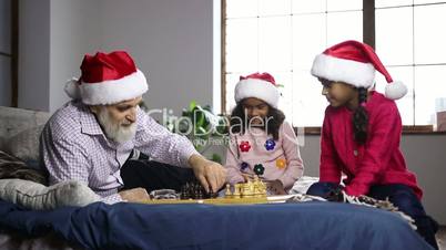 Mixed race girl playing chess with grandpa at home