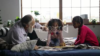 Elderly man playing chess with cute granddaughter