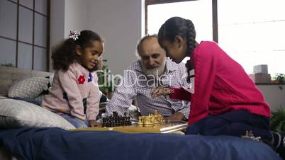 Two cute mixed race sisters playing chess at home