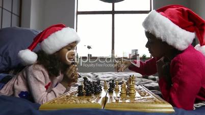 Kids in santa hats playing chess and thinking