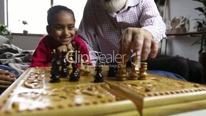 Grandfather teaching grandchildren chess at home