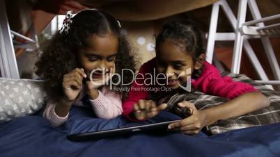 Smiling little girls working on digital tablet