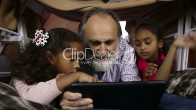 Little kids teaching grandfather to use tablet