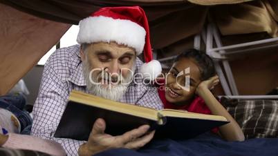 Grandpa with kids reading fairy tales on Xmas Eve