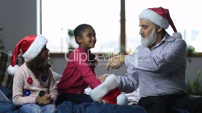 Smiling girls and grandpa playing secret santa
