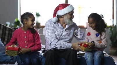 Joyful grandpa giving christmas gift to children