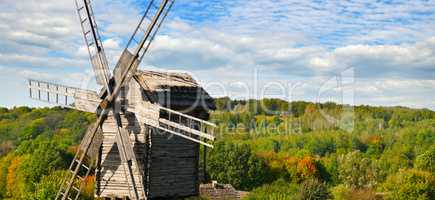 old wooden windmill in field and sky