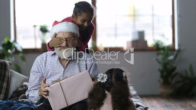 Cute little girls giving christmas gift to grandpa