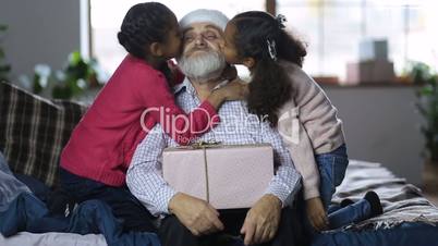 Grandchildren kissing grandfather with xmas gift