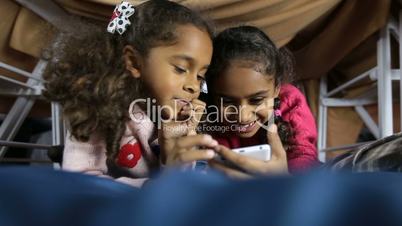 Smiling preschool girls browsing web on smartphone