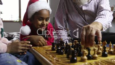 Cute little girl in santa hat watching chess game