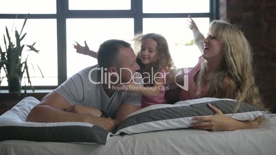 Portrait of family with daughter posing in bed