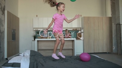 Cute little girl in pajamas jumping on bed