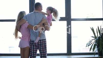 Attractive family in love embrace by the window
