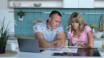 Man doing accounts together with his wife at home