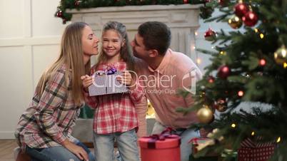 Loving parents kissing daughter on Christmas eve