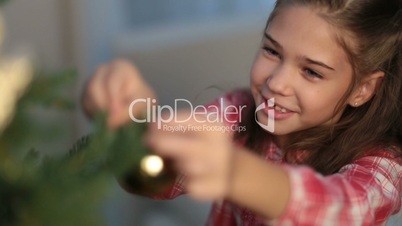 Girl hanging decorative toy ball on Christmas tree
