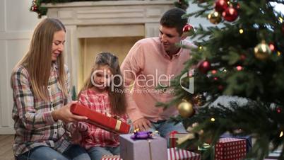 Cheerful family exchanging gifts near xmas tree