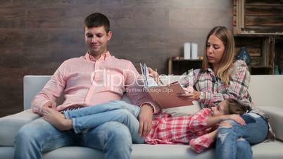 Attractive parents with child reading book at home
