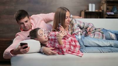 Young family spending time with electronic devices