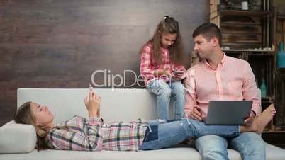 Family busy with electronic devices on sofa