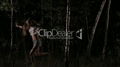 Scared woman running through forest at night