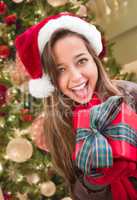 Girl Wearing A Christmas Santa Hat with Bow Wrapped Gift In Fron