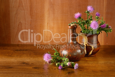 Oil and flower of milk thistle on wooden background.