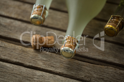 Bottles of champagne and its cork on wooden surface