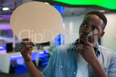 Male executive holding speech bubble in office