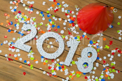 New year 2018 with party hats and confetti on wooden surface