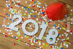 New year 2018 with party hats and confetti on wooden surface