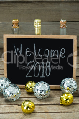 Welcome 2018 written on slate board with baubles and champagne bottle