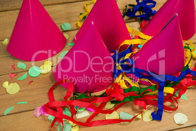 Party hats with streamers and confetti on wooden surface