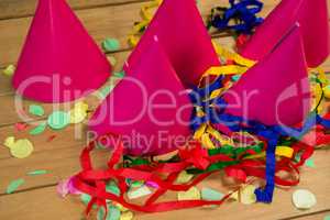 Party hats with streamers and confetti on wooden surface