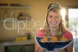 Woman holding tray of muffins in restaurant