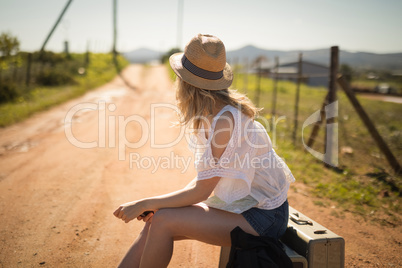 Woman with luggage waiting on a dirt track