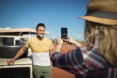 Woman taking a photo of man with mobile phone
