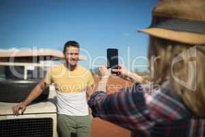 Woman taking a photo of man with mobile phone