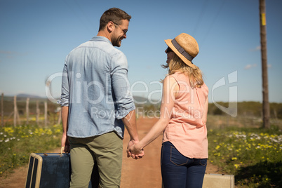 Couple walking with their luggage on a sunny day