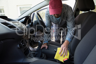 Worker cleaning seat inside the car