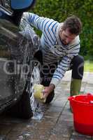 Auto service staff washing a car tyre with sponge