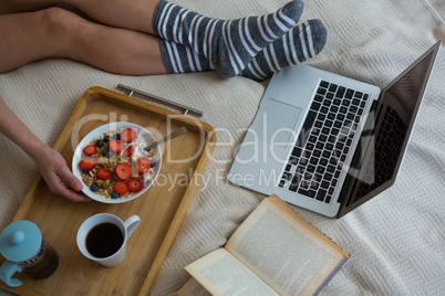 Low section of woman having breakfast on bed