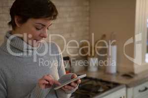 Woman using mobile phone in kitchen