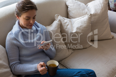 Woman using mobile phone while having coffee