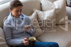 Woman using mobile phone while having coffee