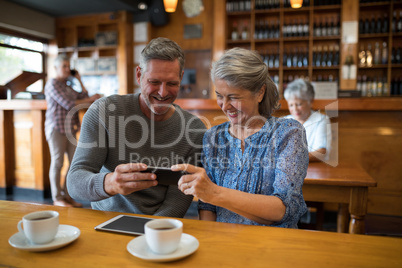 Happy senior couple looking their photos on mobile phone