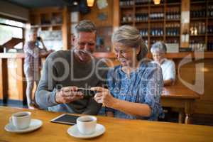Happy senior couple looking their photos on mobile phone