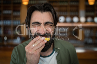 Man biting into lemon wedge after having tequila shot